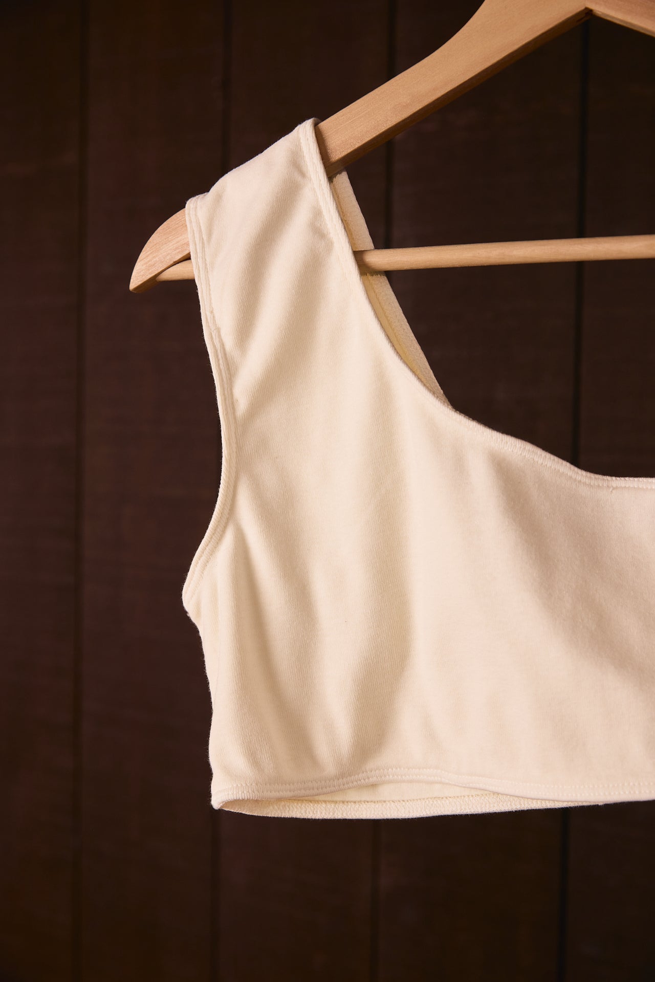 Climate Beneficial cotton top on a wooden hanger against a dark background