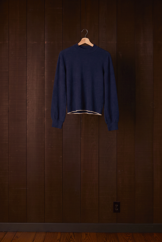 Tall women's indigo merino wool top on a hanger against a dark wooden wall