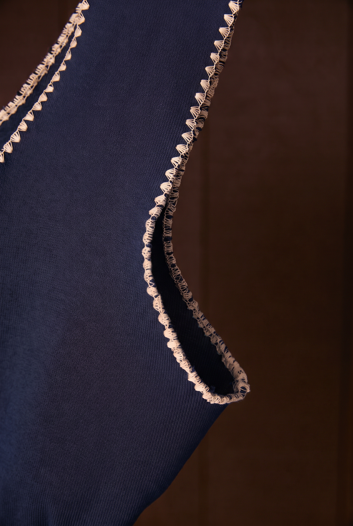 Close-up of cream shell-stitch armhole on indigo cotton