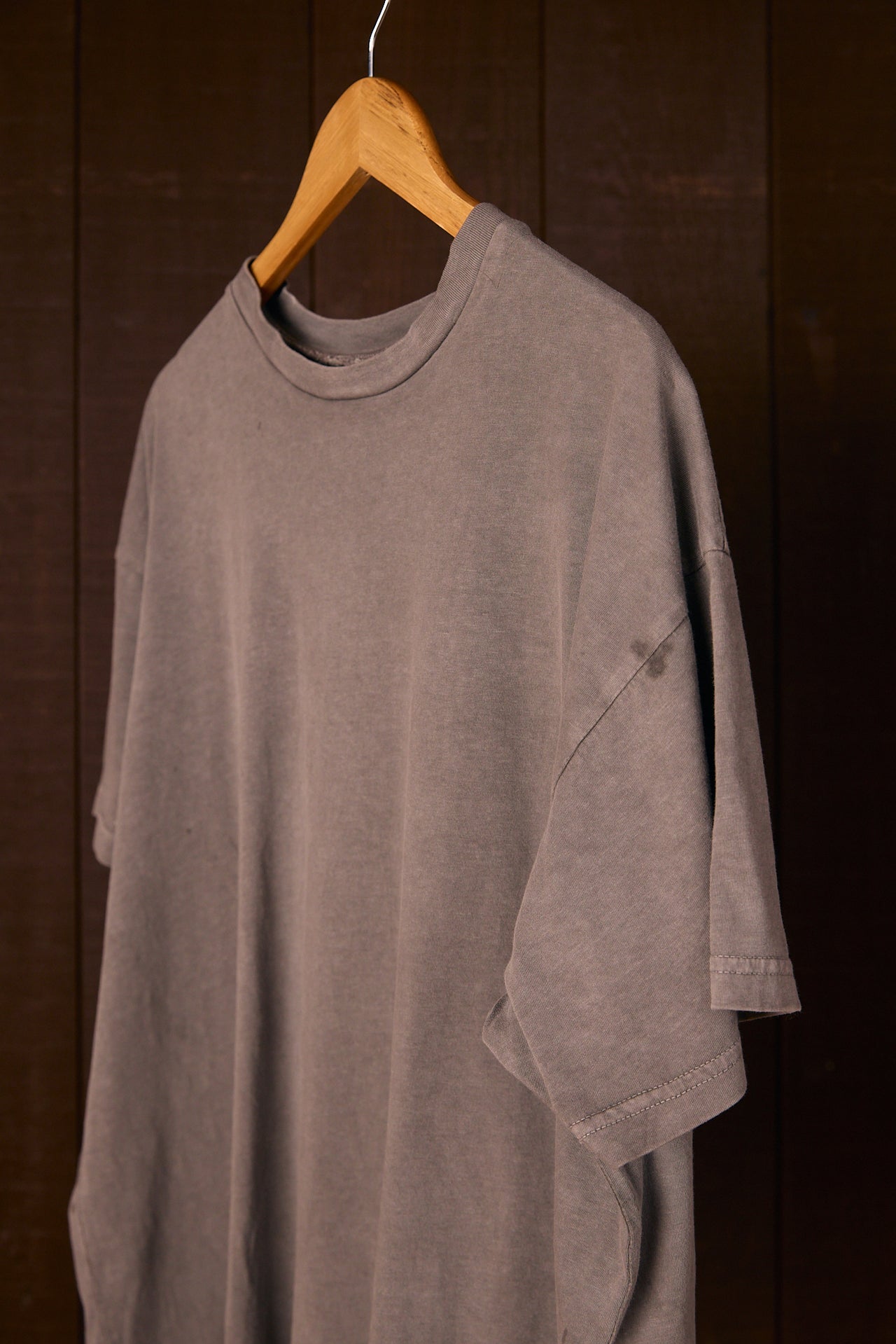 Climate Beneficial cotton t-shirt on a wooden hanger against a dark background