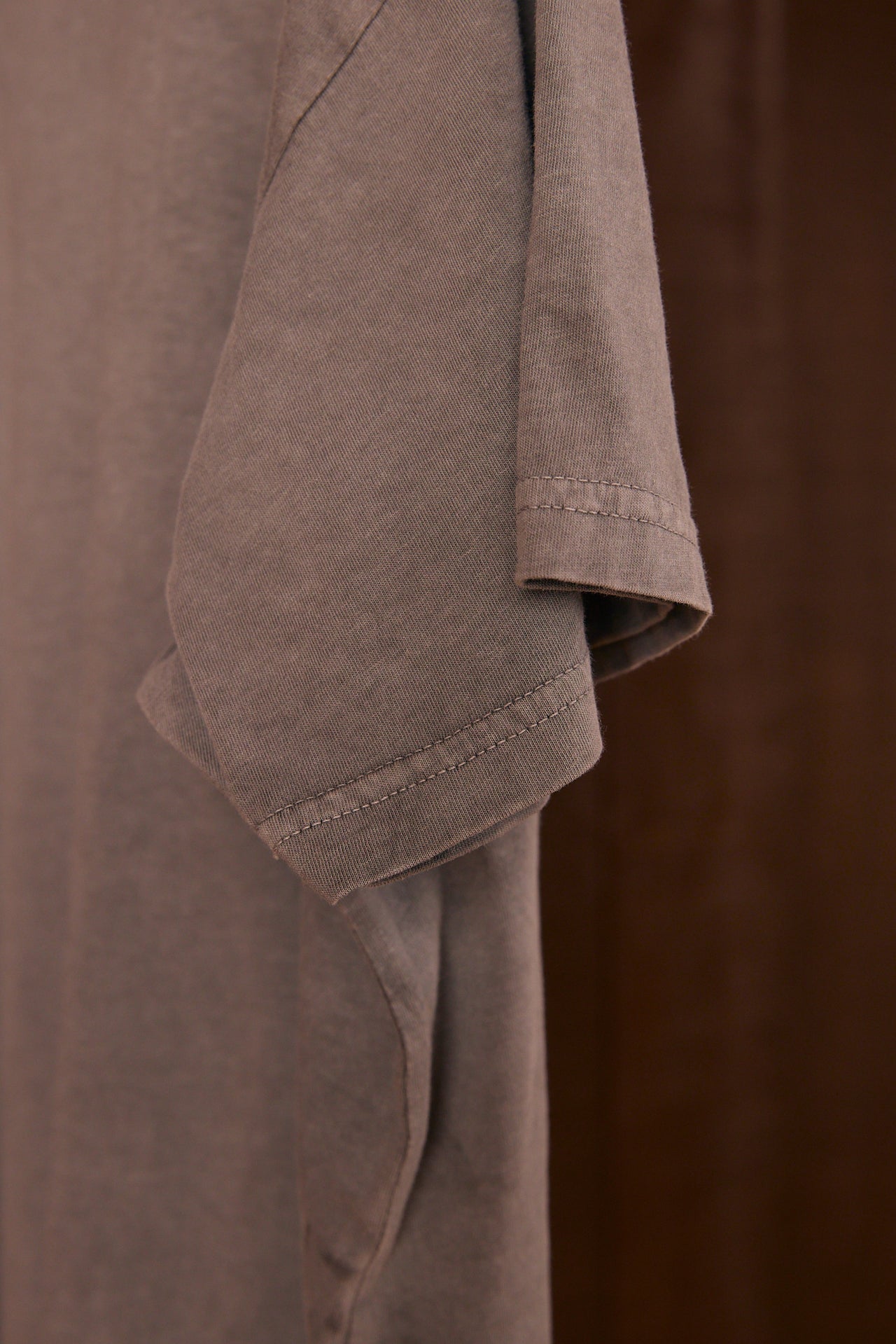 Close-up of climate beneficial cotton fabric with a visible seam on a dark brown background