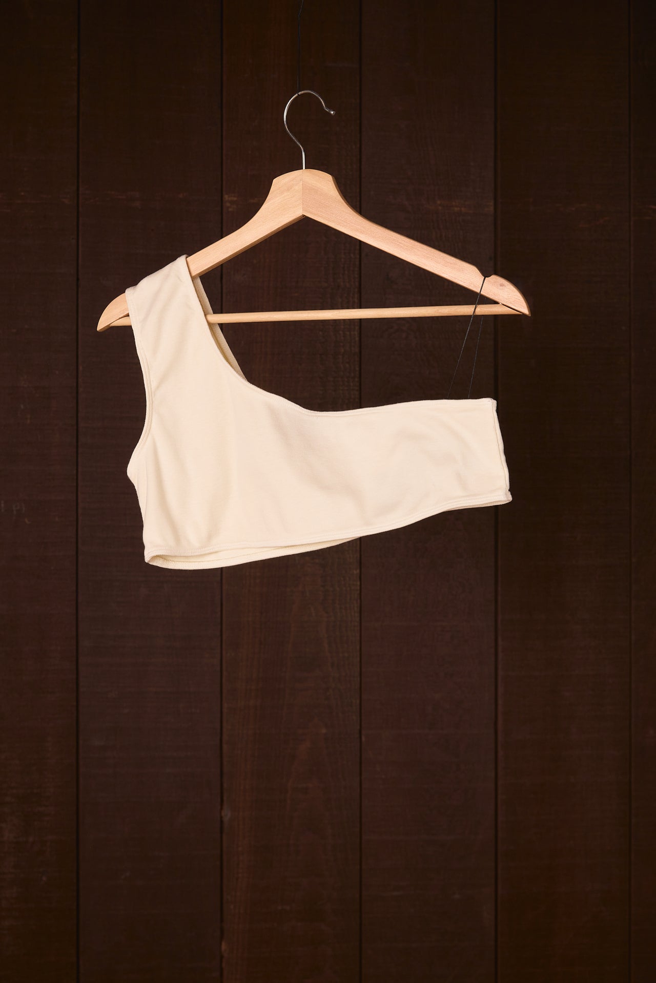 climate beneficial garment on a wooden hanger against a dark wooden background