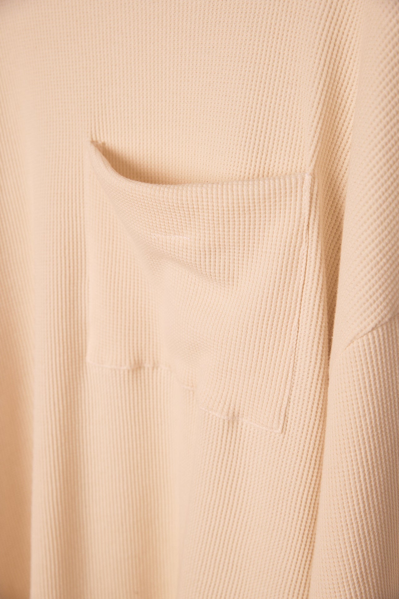 Close-up of beige waffleknit fabric with a pocket