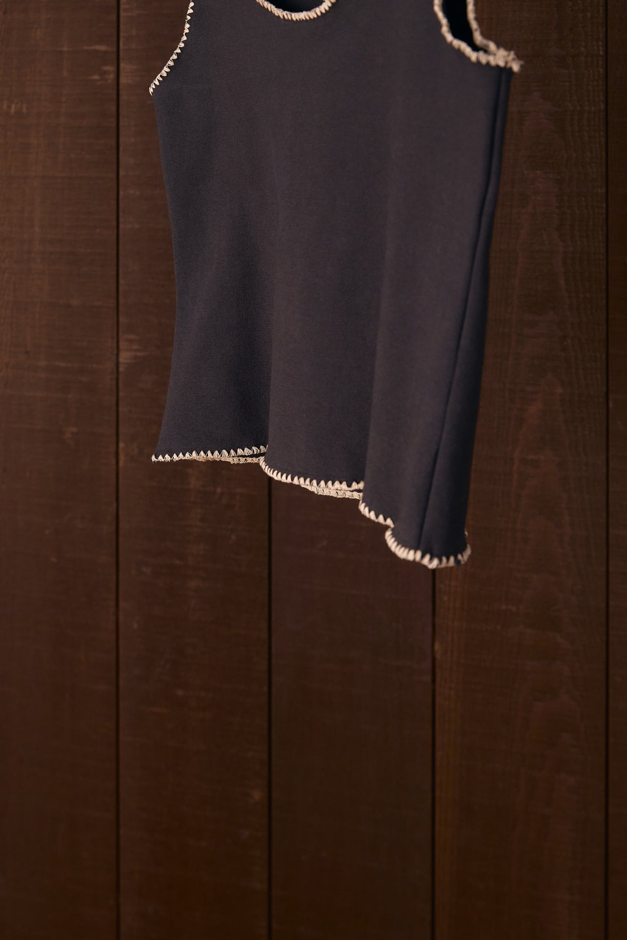 Black sleeveless top with shell stitch hem on a wooden background