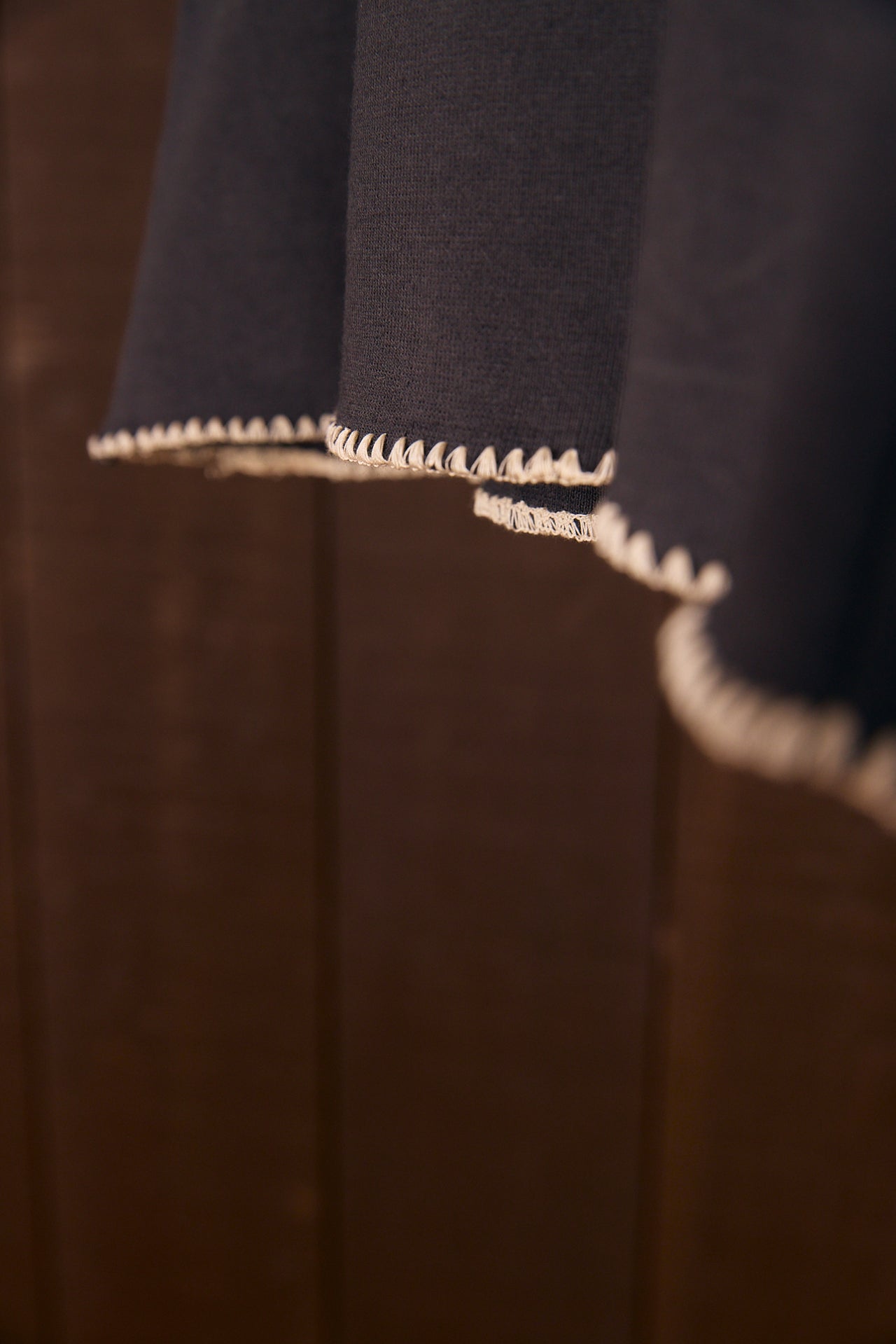 Close-up of a dark fabric with shell stitch on a brown background