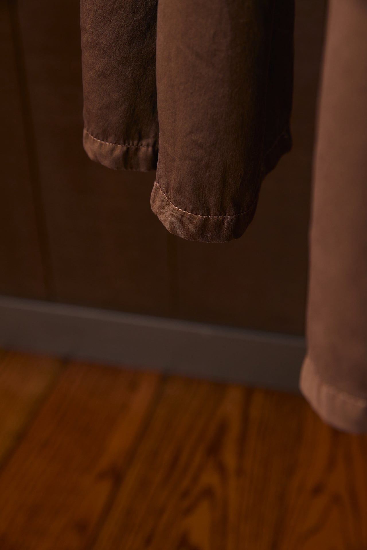 Brown pants hanging on a rack with a wooden floor in the background