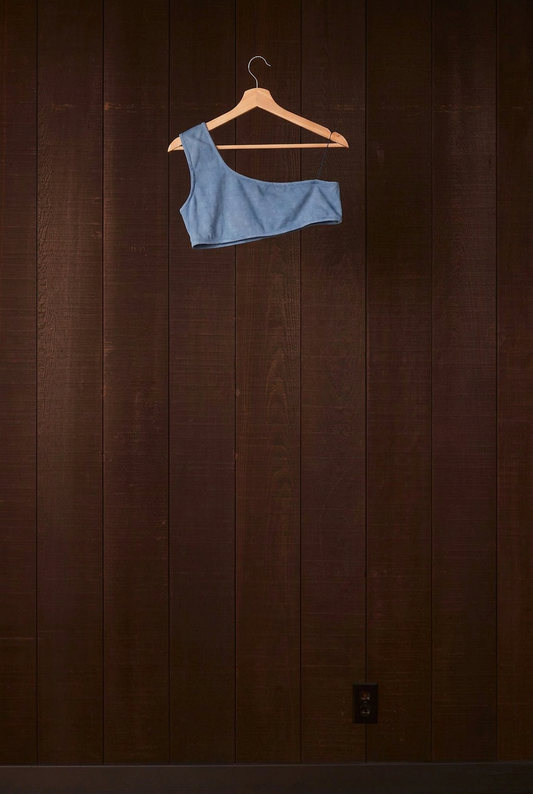Indigo plant-dyed cotton Una Bra on a wooden hanger against a dark wood wall