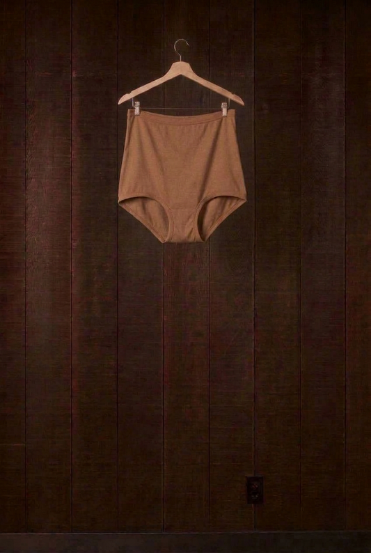 Cutch plant-dyed walnut cotton Mamita's Highwaist Panty on a wooden hanger against a dark wood wall