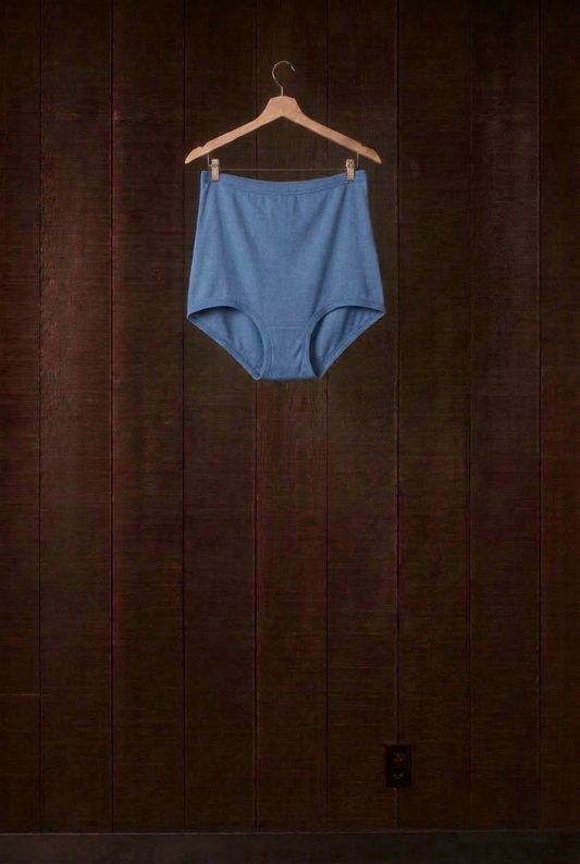 Indigo plant-dyed cotton Mamita's Highwaist Panty on a wooden hanger against a dark wood wall