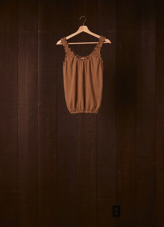 Cutch plant-dyed walnut cotton jersey Cloud Camisoul on a wooden hanger against a dark wood wall