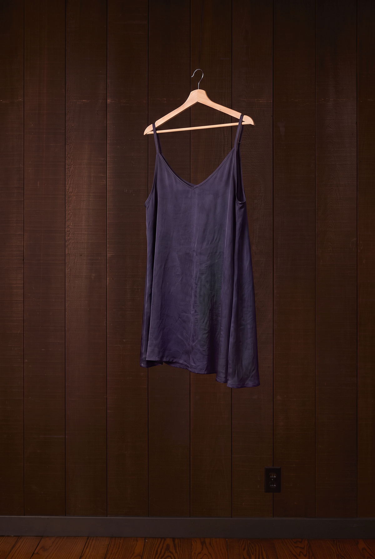 Indigo silk camisole hanging at an angle on a wooden hanger